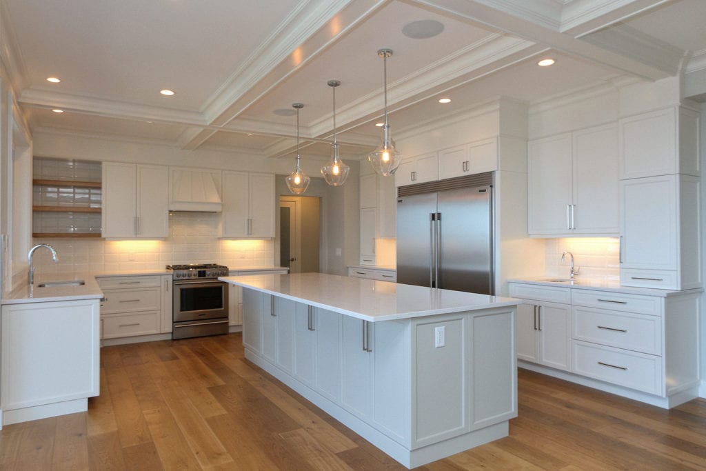 Custom built kitchen by Stark Homes with white cabinets, stone countertops, and energy-efficient appliances, part of sustainable building practices.