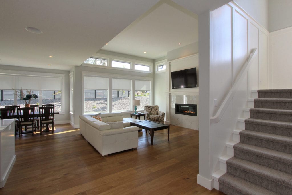 Interior image of living and dining area in a custom built home by Stark Homes with eco-friendly flooring, white walls, fireplace, and white sofa.