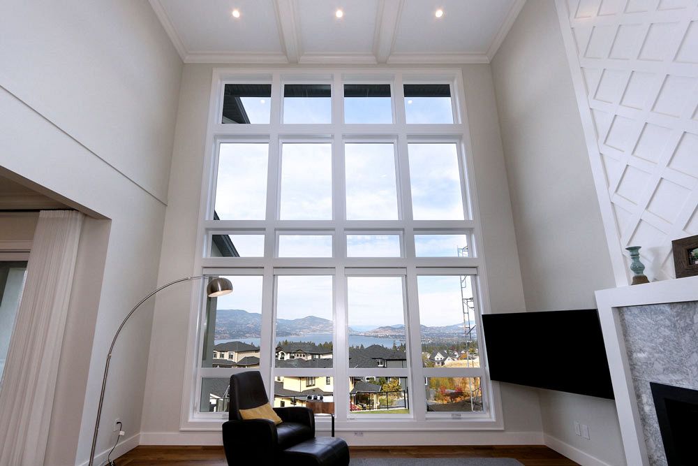 Living room view of big lake-facing windows with a chair and tv in foreground, highlighting energy efficient windows in sustainable building practices.